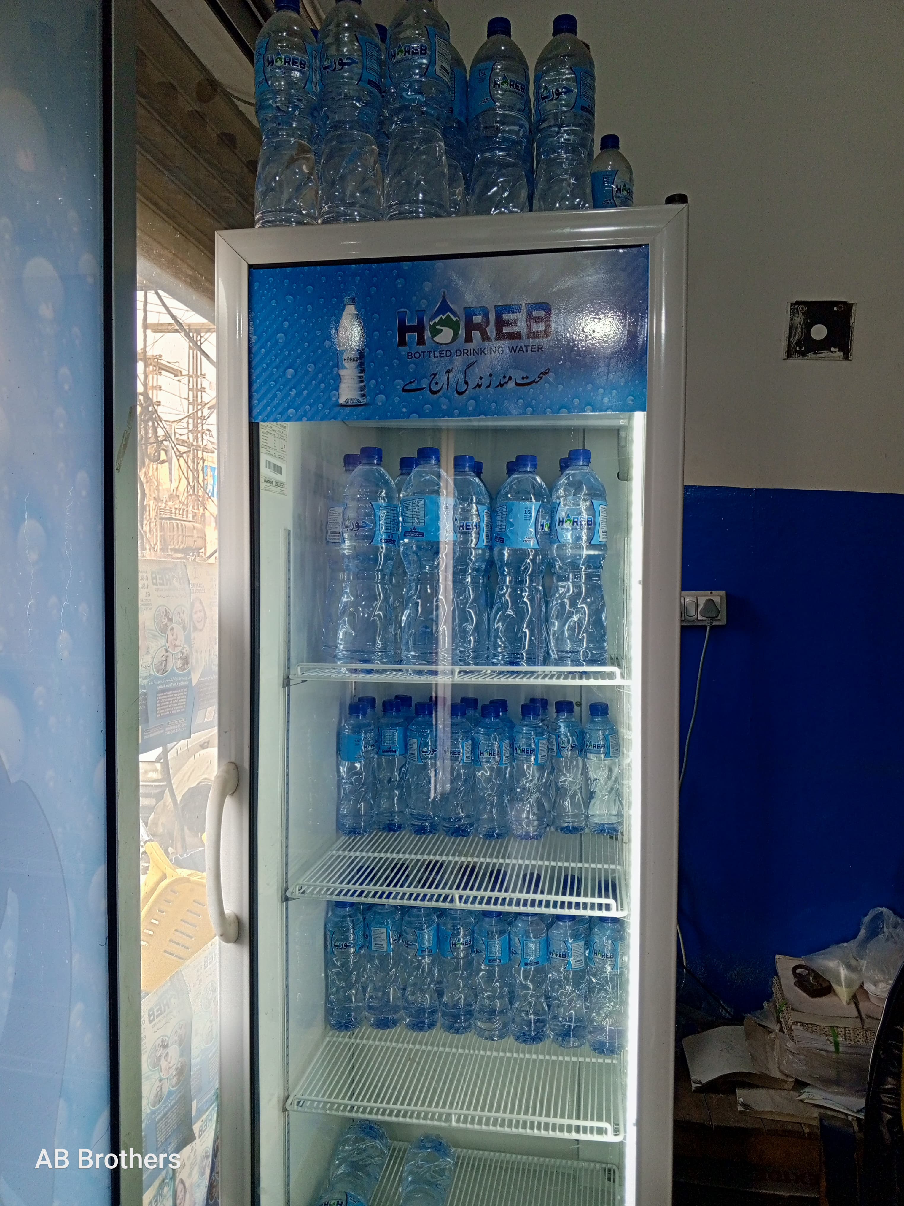A refrigerated display of Horeb bottled water in various sizes