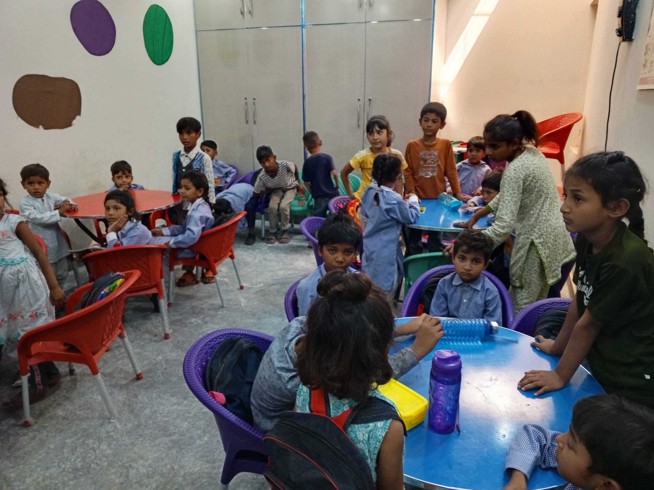 Children in a Joshua School classroom, seated at tables with their school bags